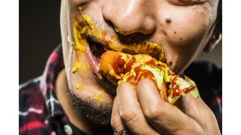 Mid adult man eating a hot dog,close up shot