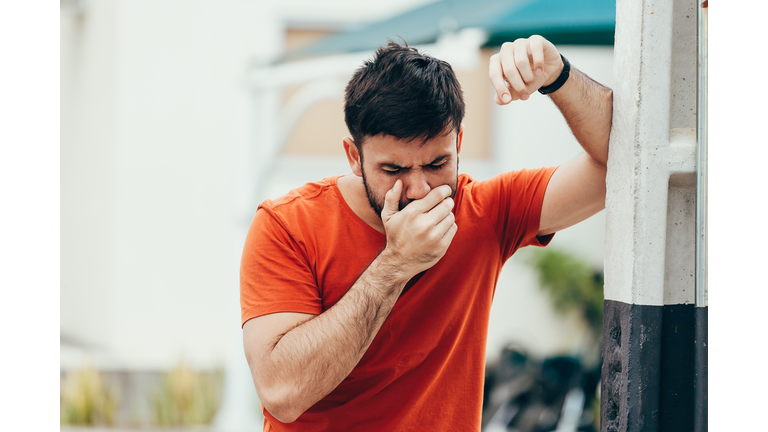 Portrait of young man drunk or sick vomiting outdoors