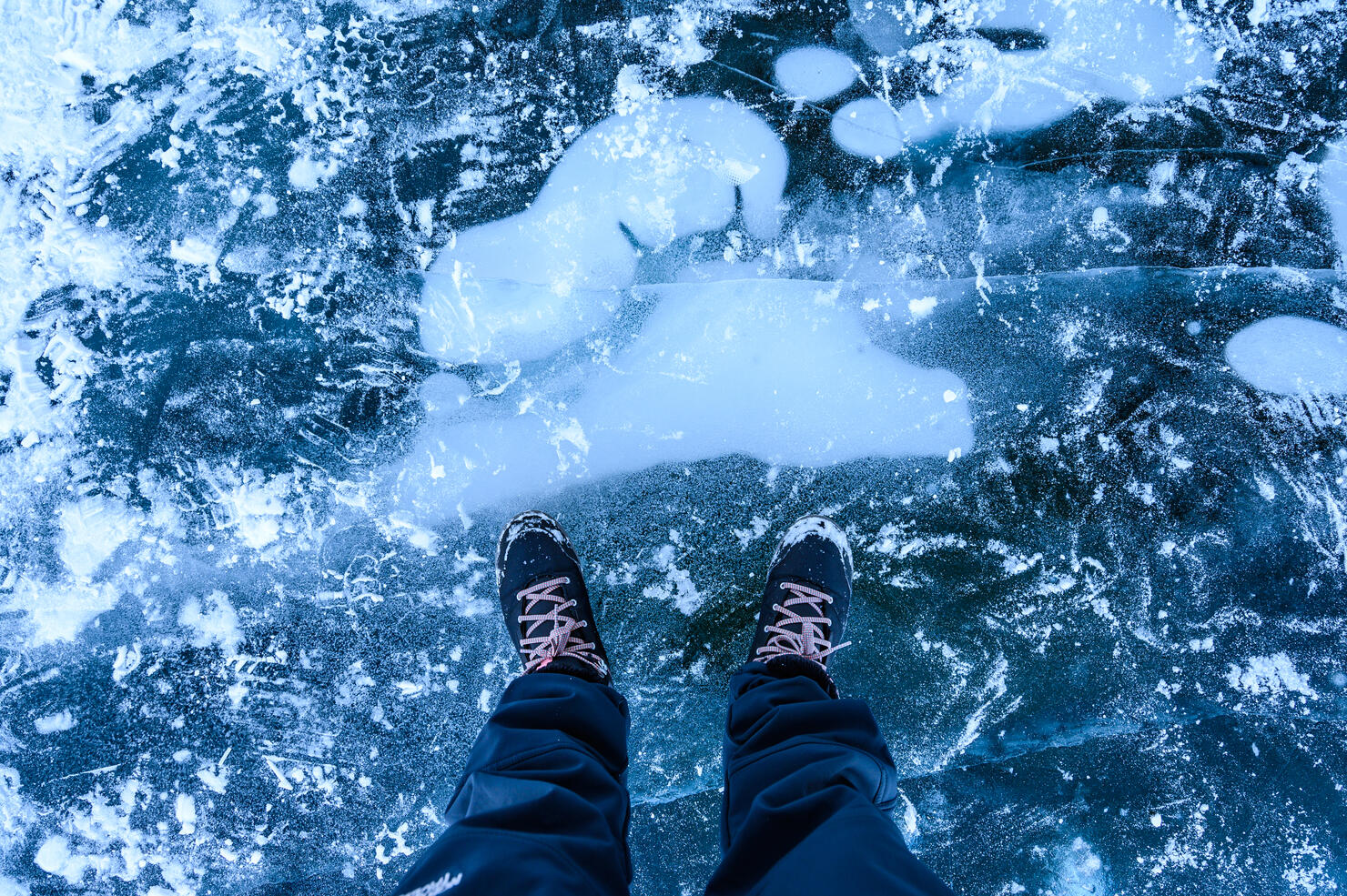 A foot of tourist standing on the cracks surface of frozen lake Baikal in the winter season of Siberia, Russia.