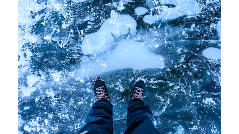 A foot of tourist standing on the cracks surface of frozen lake Baikal in the winter season of Siberia, Russia.