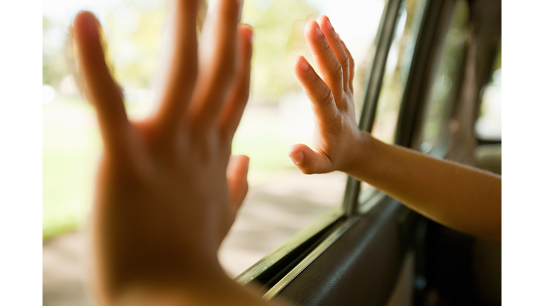 Child's hands touching car window