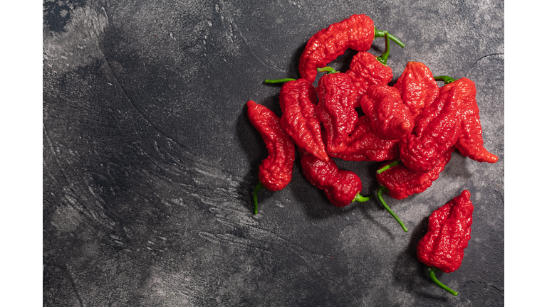 Bhut Jolokia peppers atop dark textured backdrop, top view, copy space. Ghost chile peppers, a Capsicum chinense fruits