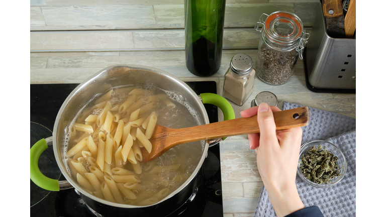 Cooking Italian pasta at home. A girl or a woman cooks and stirs Penne pasta in a saucepan. Vegetarian and vegan food. Cooking lessons. Sustainable development, ethical consumption. Step-by-step instructions, do it yourself. Step 4.