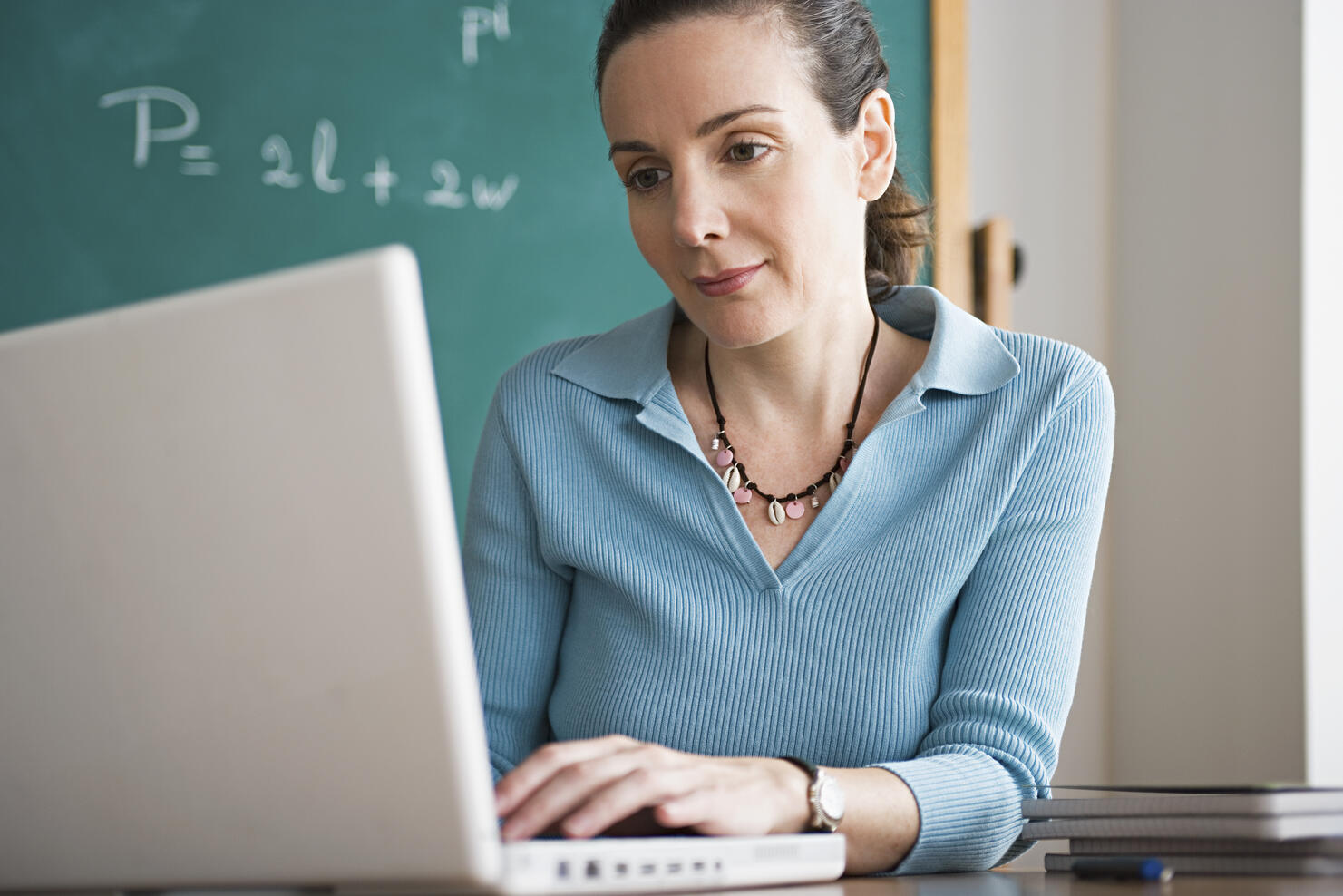 USA, California, Los Angeles, Happy female teacher using laptop in classroom