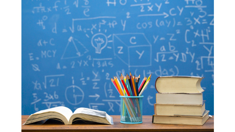 Back to school supplies. Books and blackboard on wooden background