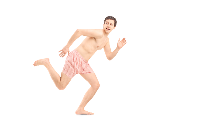 An embarrassed naked man in underwear running away