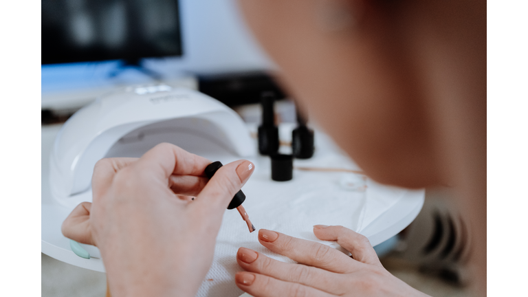 Woman painting her nails at home during pandemic