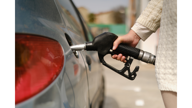 unrecognizable woman using gas pump to add fuel to her car during energy crisis