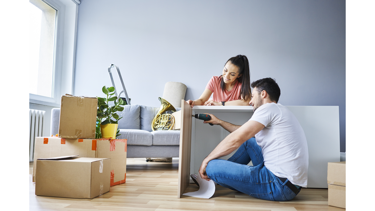 Couple in new apartment assembling furniture together