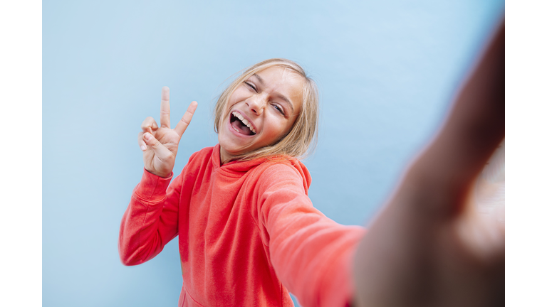 Portrait of a beautiful blonde teenage girl with eyes taking a selfie.