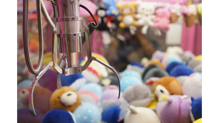 Close up of the doll claw machine of games arcade in shopping mall