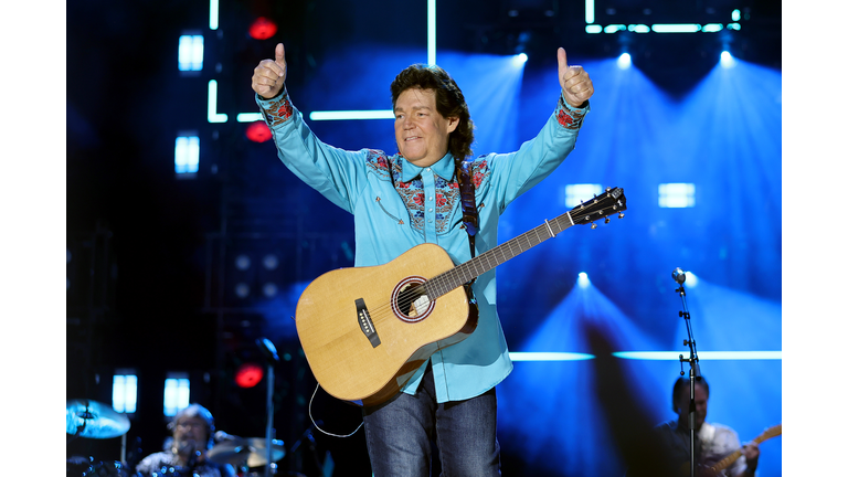 Marty Raybon of Shenandoah in a blue shirt and jeans giving two thumbs up at the audience.