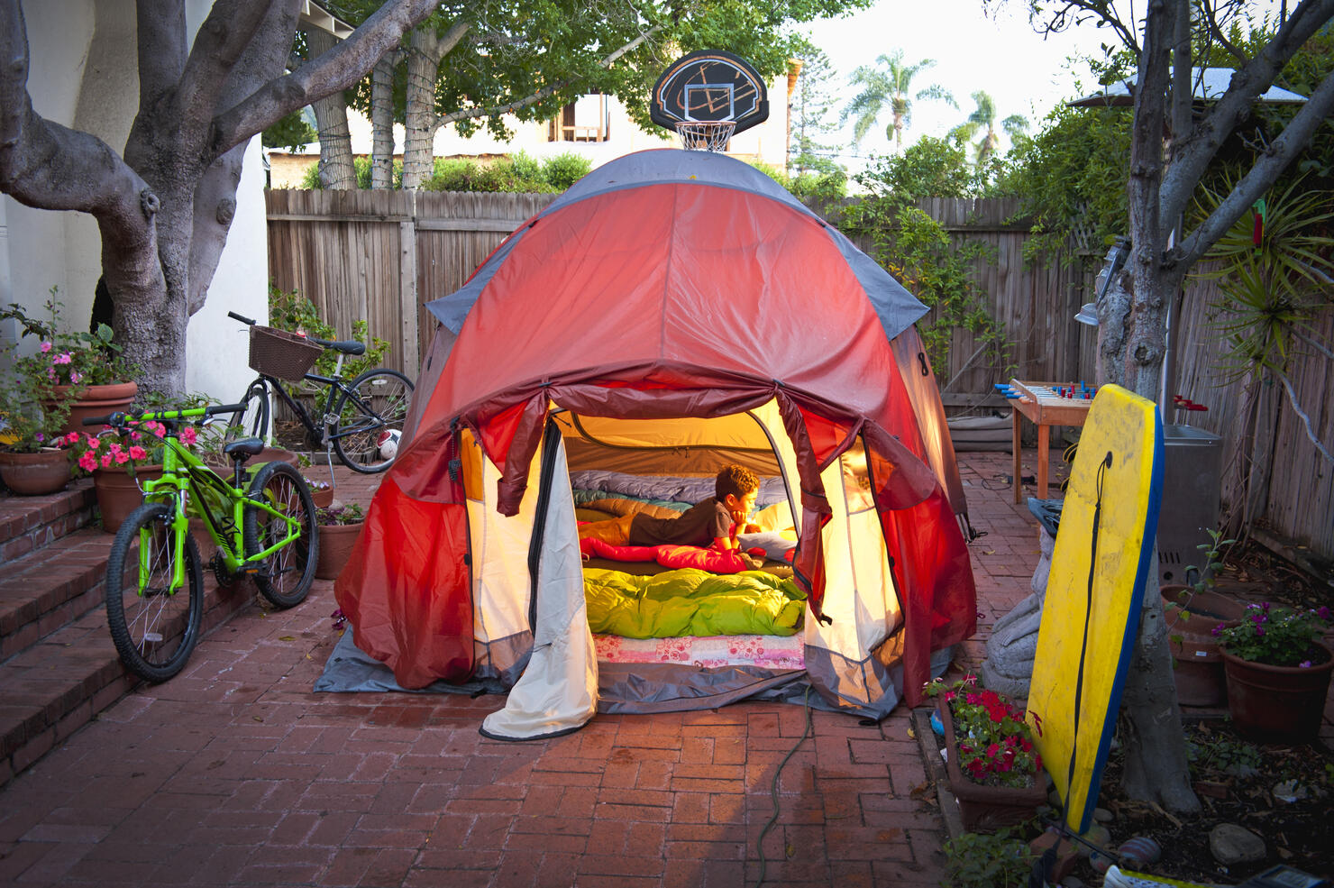 boy reading in tent in side yard of house