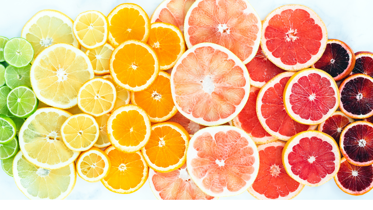 Flat Lay of Rainbow of Vibrant Citrus Fruit Slices on White