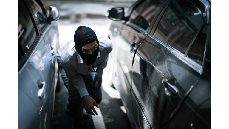 robber in black mask with car. robbery and crime concept.