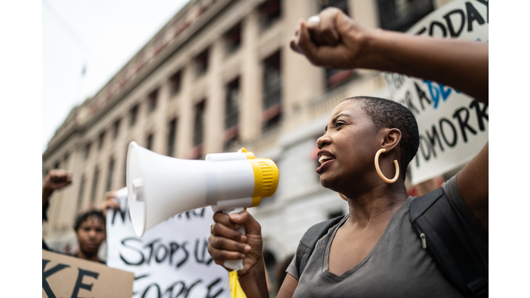Mid adult woman leading a demonstration using a megaphone