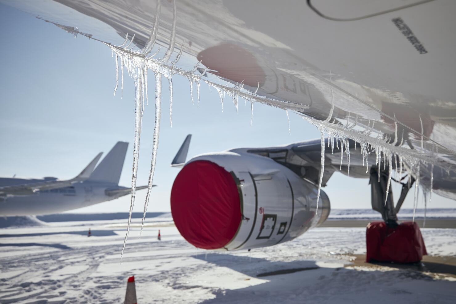 Selective Focus On Icicles From Airplane In Frosty Day. Grounded Planes At Snowy Airport.