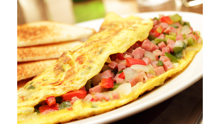 A folded egg omelets filled with chopped ham and vegetables