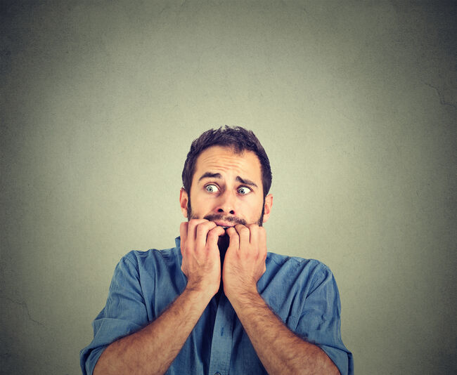 Anxious young man biting his nails fingers freaking out