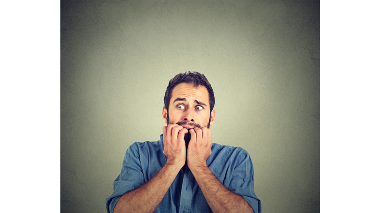 Anxious young man biting his nails fingers freaking out