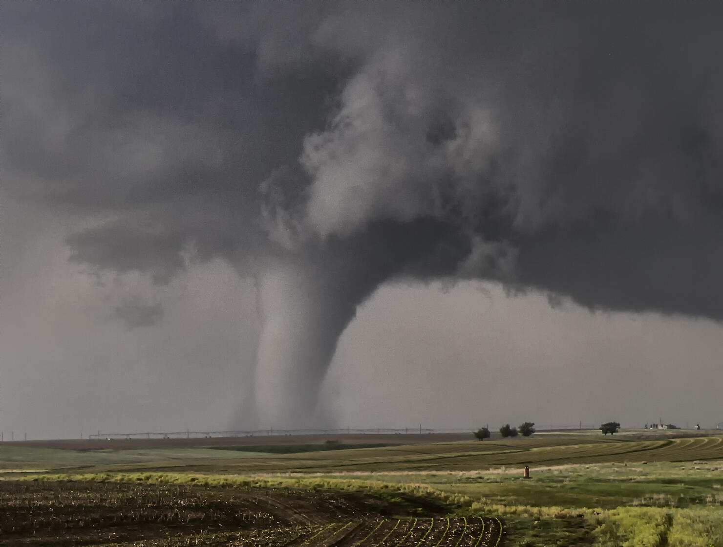 A large cone tornado touches down over the open prairie