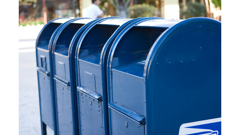 Four bright blue USPS mailboxes in a row