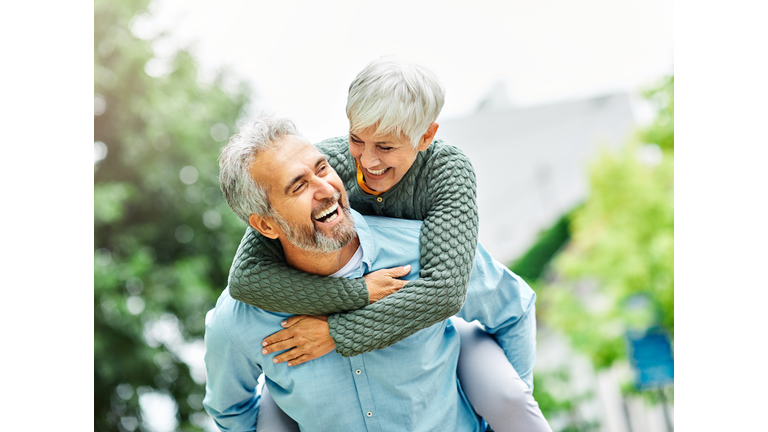woman man outdoor senior couple happy lifestyle retirement together smiling love piggyback active mature