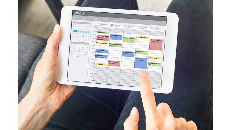 Calendar app on tablet computer with planning of the week with appointments, events, tasks, and meeting. Hands holding device, time management concept, organization of working hours planner, schedule