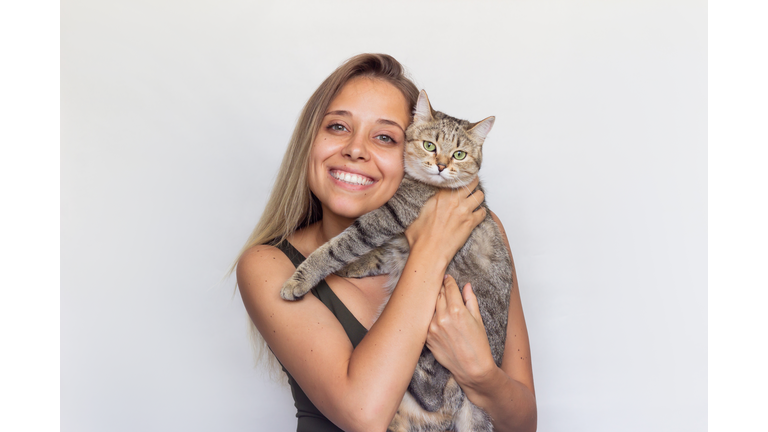 A young blonde woman holds Tabby cat