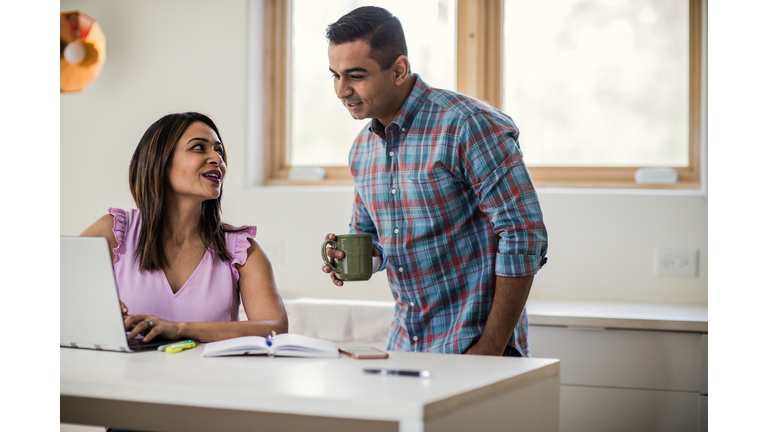 Husband and wife using laptop in kitchen