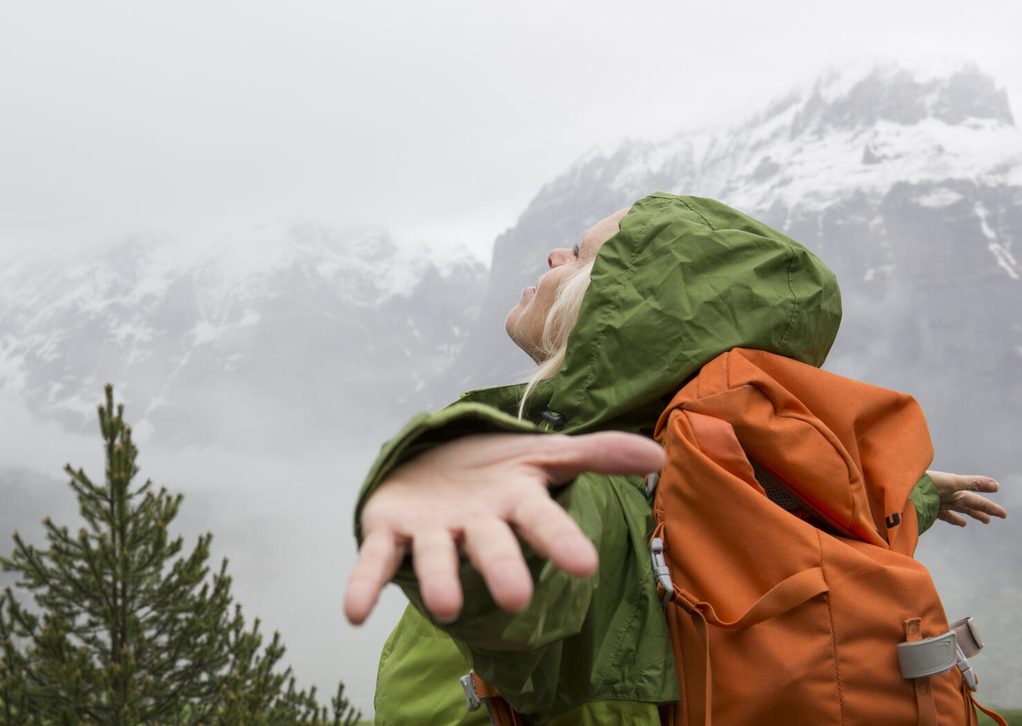 Female hiker spreads arms to embrace mountain mist