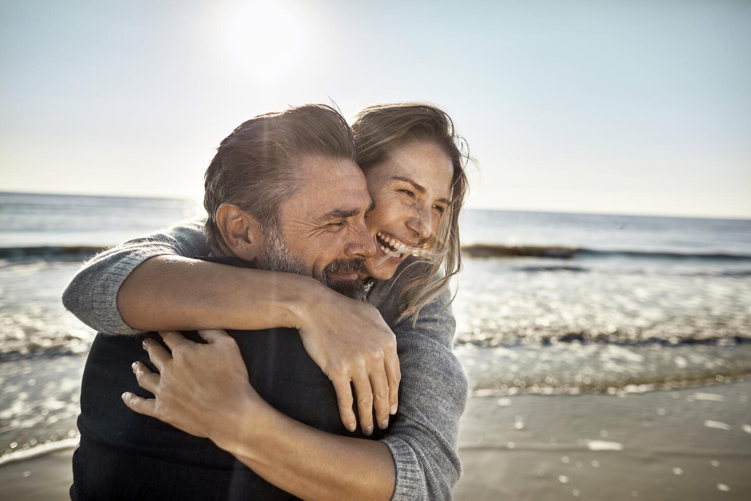 Carefree mature man and woman hugging at the sea