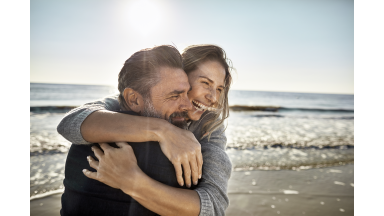 Carefree mature man and woman hugging at the sea