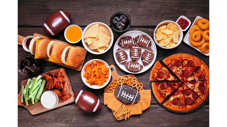 Super Bowl or football theme food table scene, top view on dark wood