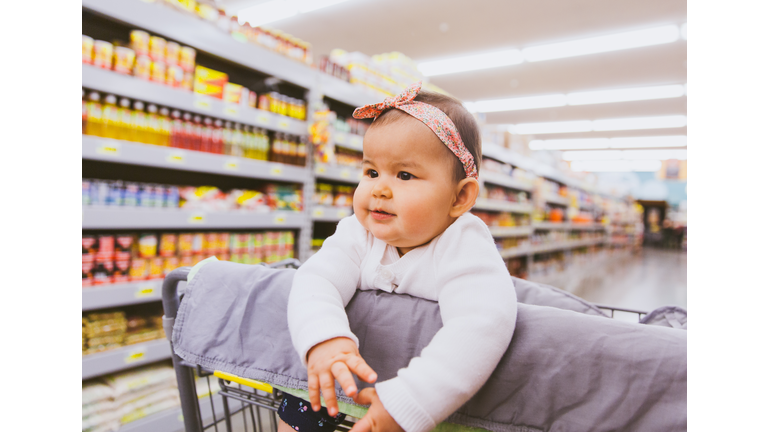 Baby girl sitting in grocery cart