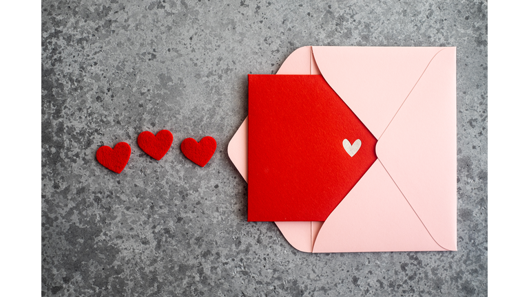 Close-up of pink envelope with red postcard, top view. Valentine's Day card.