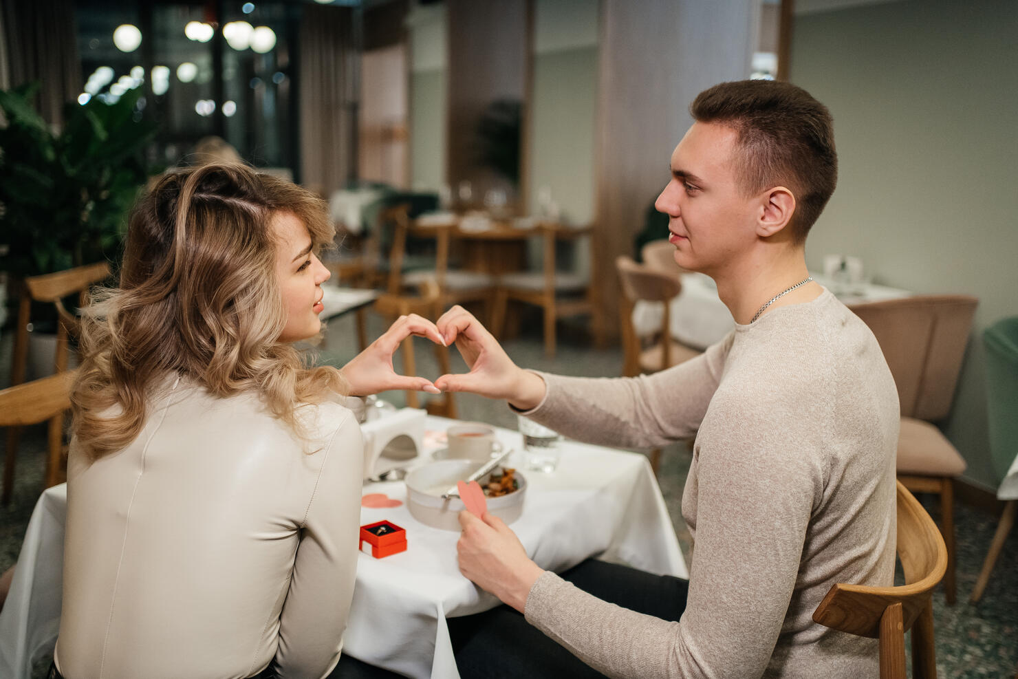 couple in love crossed their arms in the shape of a heart in a restaurant on valentine's day