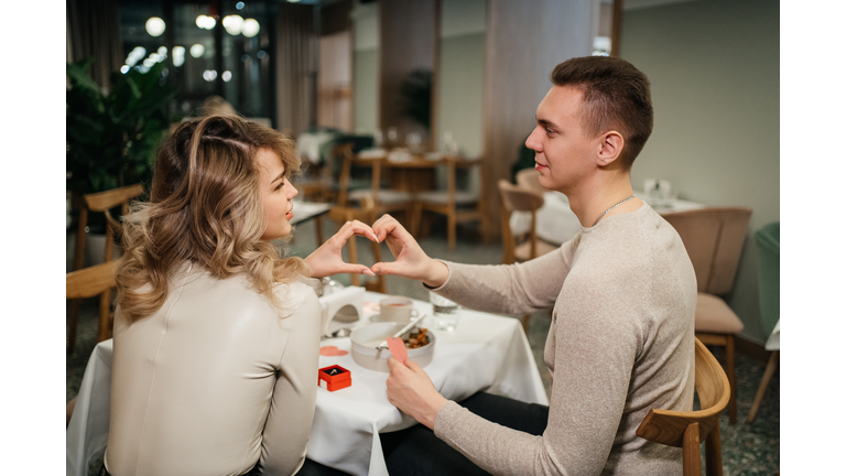 couple in love crossed their arms in the shape of a heart in a restaurant on valentine's day