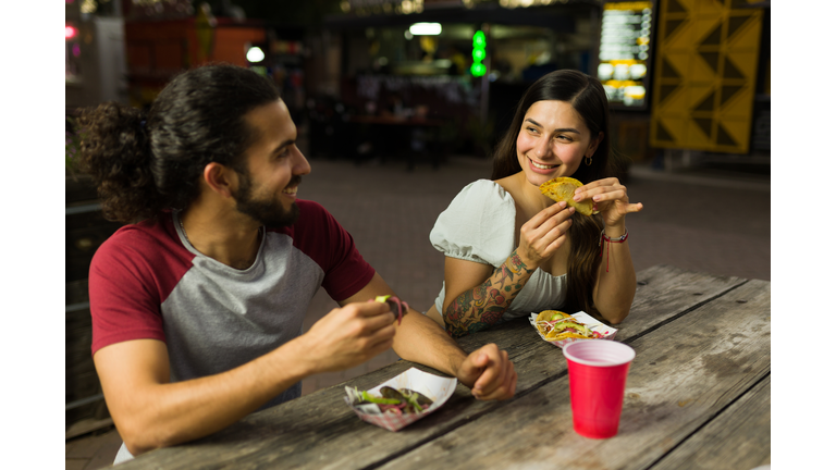 Attractive couple eating mexican tacos from the food truck