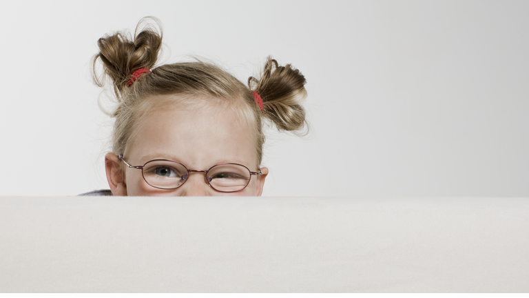 Little girl peeking over top of sofa