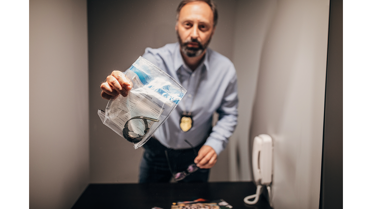 Male detective holding evidence bag in prison visit room