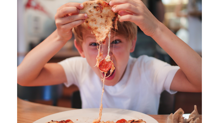 Portrait Of Boy Eating Pepperoni Pizza