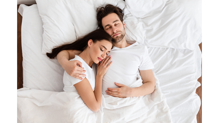 Married Couple Sleeping Embracing In Comfortable Bed Indoor, Top View