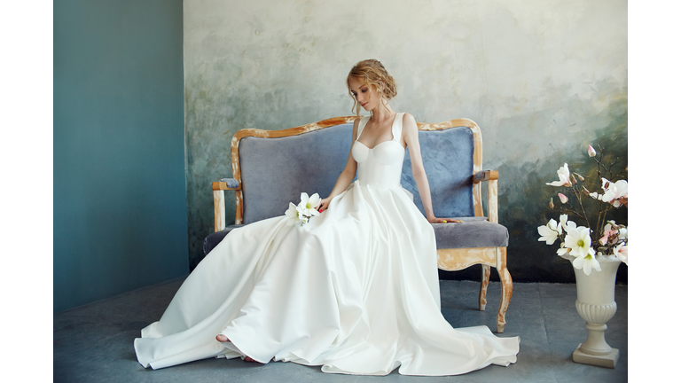 Full Length Of Bride Sitting On Sofa Against Wall