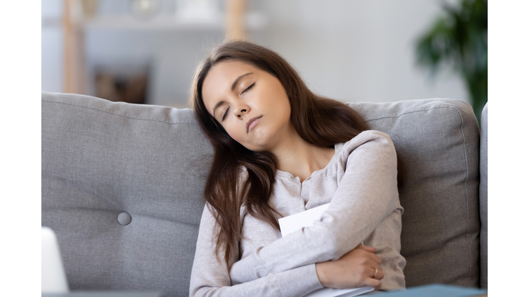 Tired female fall asleep on couch with book in hands