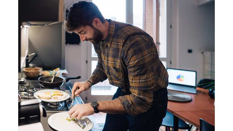 Mid adult man plating food at kitchen counter
