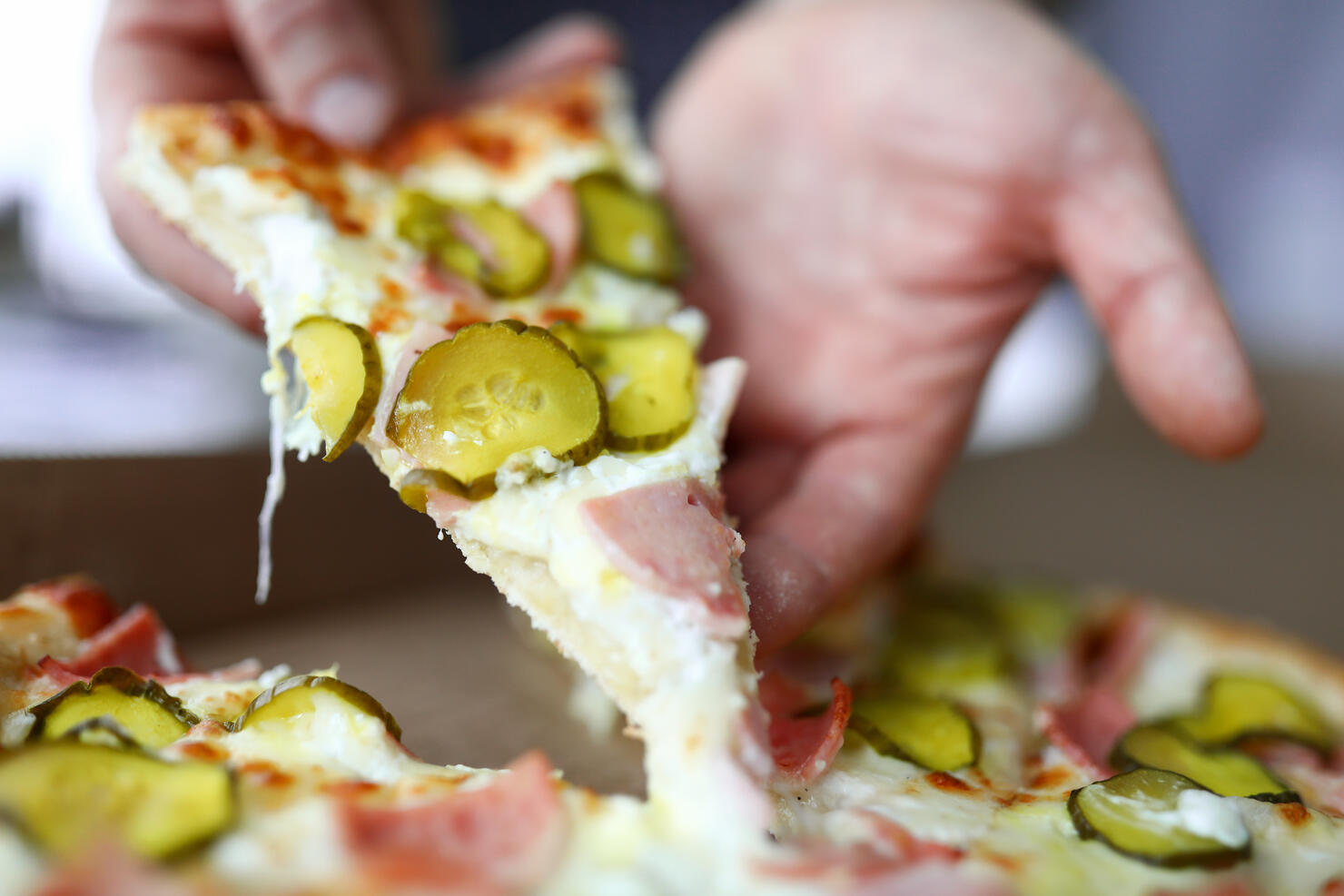 Male arms holding big piece of tasty fresh pizza