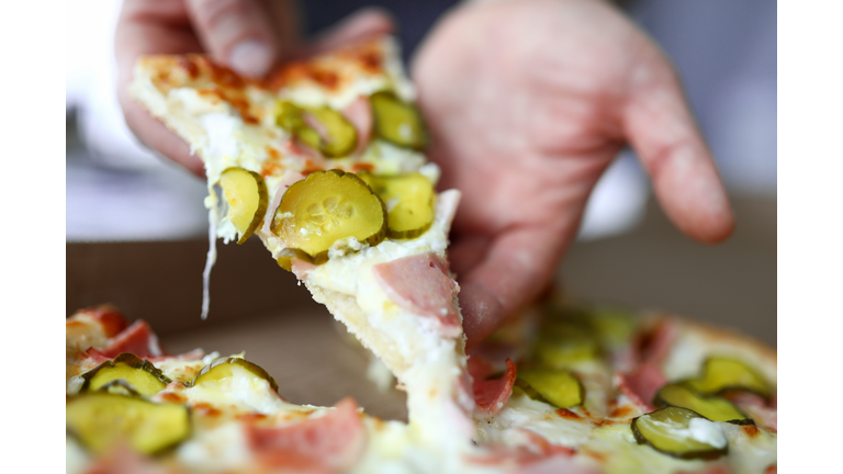 Male arms holding big piece of tasty fresh pizza