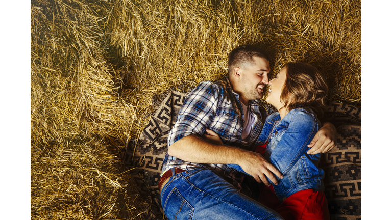 Caucasian couple kissing in haystacks