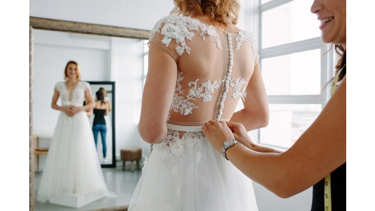 Making final touch on tailor made gown in bridal shop